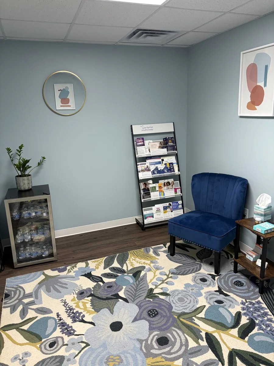 Waiting room corner at Smither Psychiatry with a navy velvet chair and complimentary water